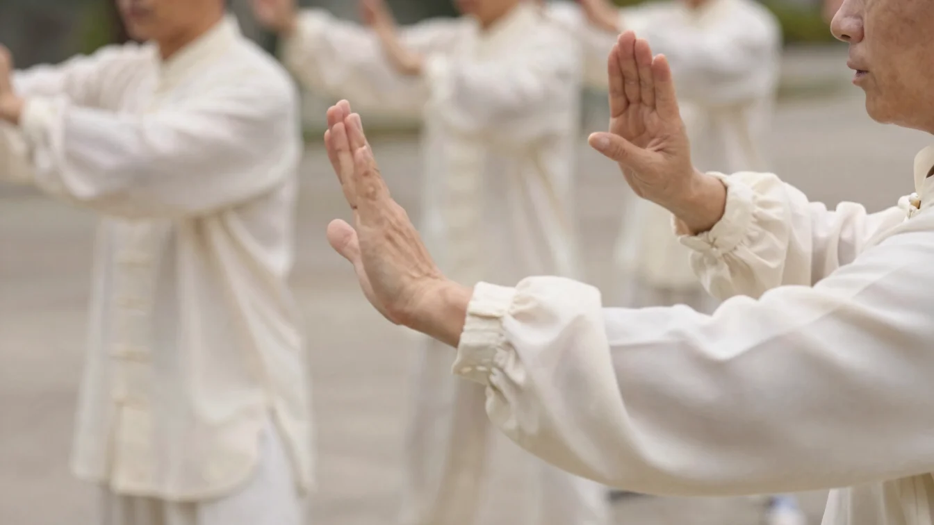 Close view of hands and forearms moving through a slow Qi Gong ar